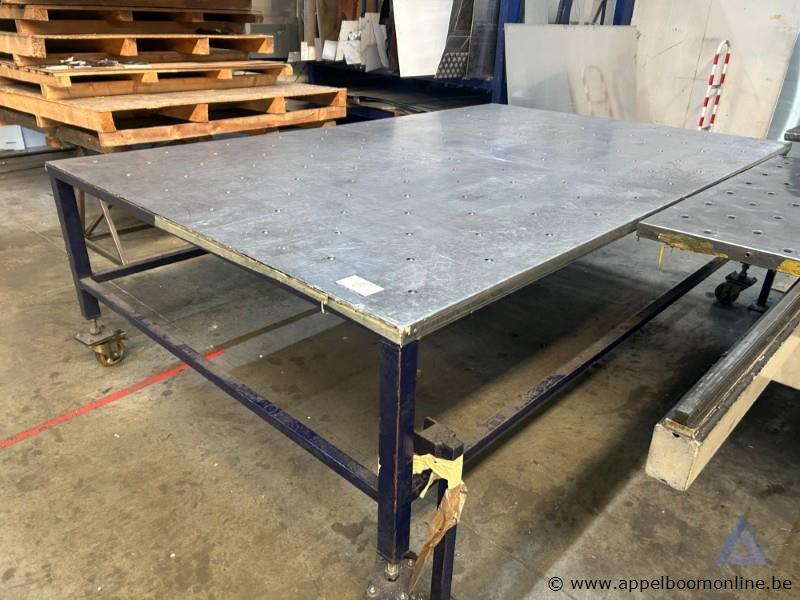 Grote metalen werktafel met een geperforeerd metalen blad. Voorzien van wielen
